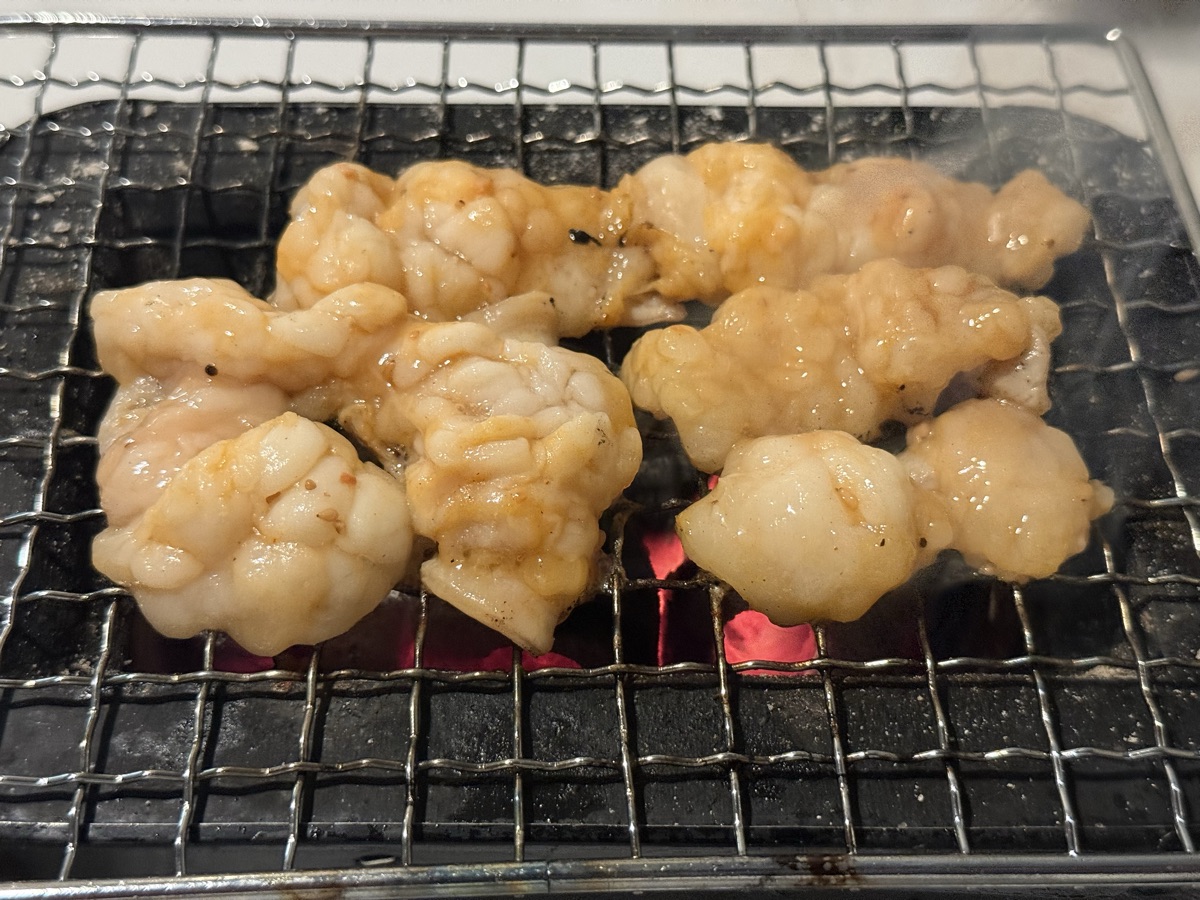 炭火で焼く味付きシマチョウ。脂が落ちて煙が出はじめている